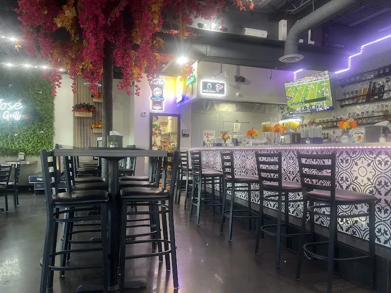 Interior of Don Jose Taco Bar with decorative floral ceiling, bar seating, and TV.