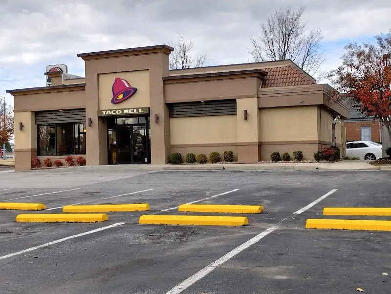 Taco Bell restaurant exterior with empty parking lot and yellow wheel stops.